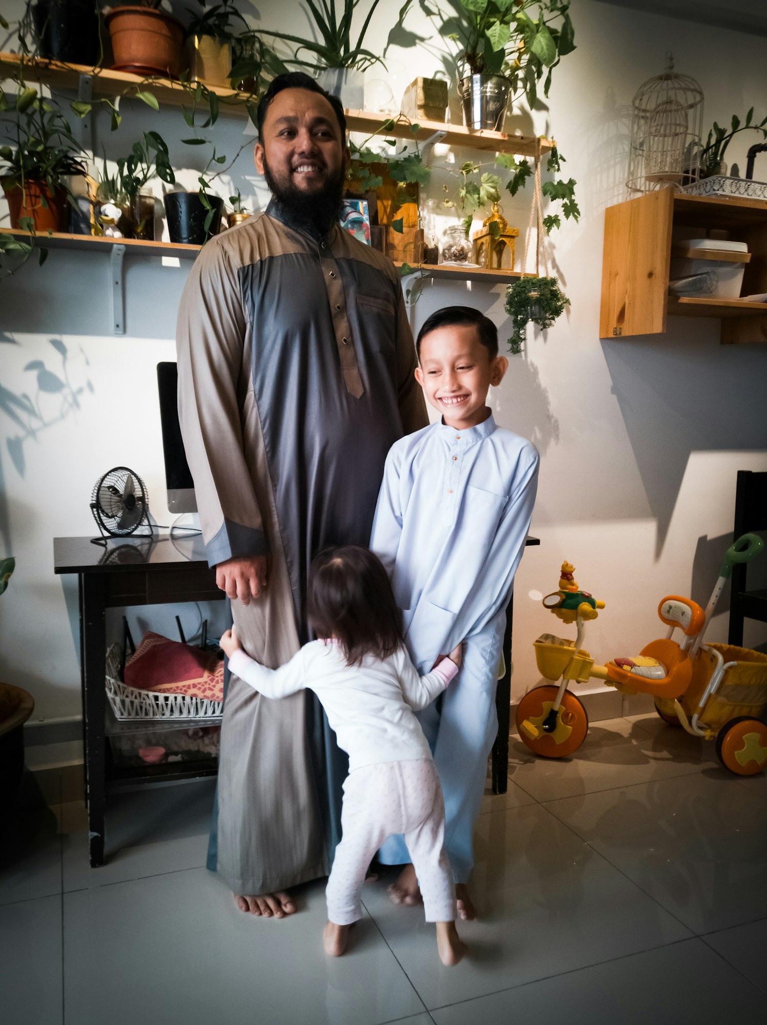 Father and children wearing traditional costume at home during Eid Muslim celebrations.