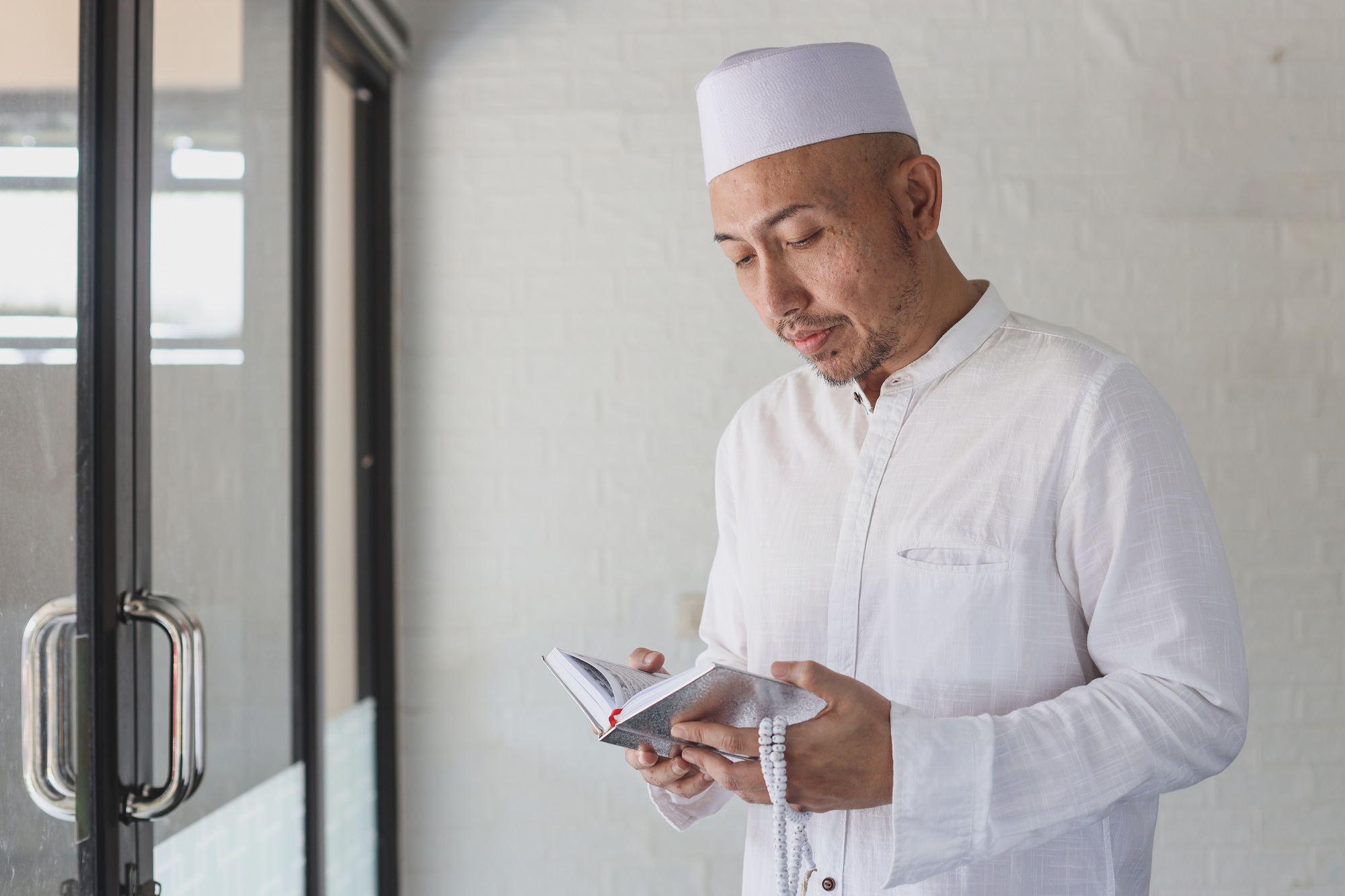 Asian man reading the holy Quran at mosque